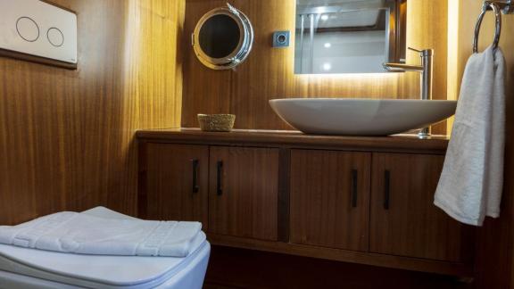 Guest bathroom of the Oggusto trawler yacht with wooden details, modern sink, and bright design.
