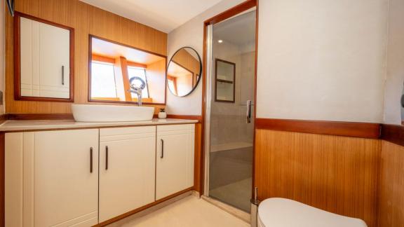 White cabinets, sink and glass shower in bathroom of Lila yacht near Fethiye.