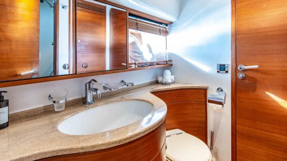The bathroom of Parodia II in Mallorca features wooden cabinets marble countertop large mirror and small window.