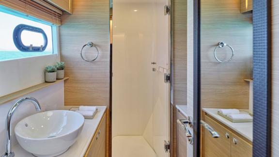 Kompaktes Bad mit Holzdetails, Duschkabine und Fenster mit Meerblick.