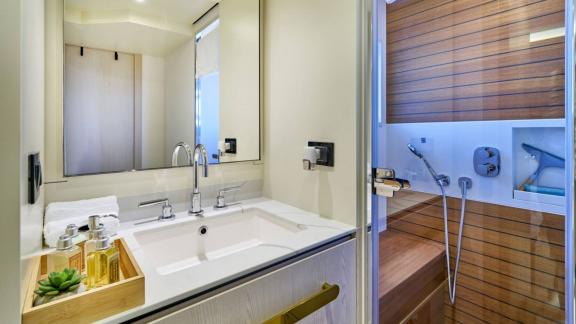 Holzverkleidete Dusche und großer Waschtisch bieten elegantes Ambiente an Bord.