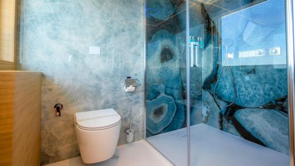 Das Bad der Renata besticht durch Glasdusche und Marmoroptik-Wände für ein luxuriöses Ambiente.