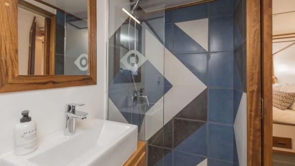 The bathroom includes a sink, mirror, and a spacious shower with glass door.