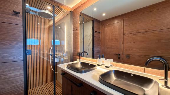 Люкс ванная с двойной черной раковиной и отделкой из дерева для 12 гостей.