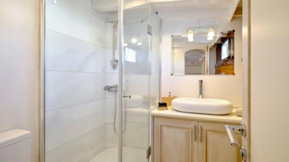 The bathroom of White Pearl gulet in Athens features a shower cabin, sink and storage cabinets.