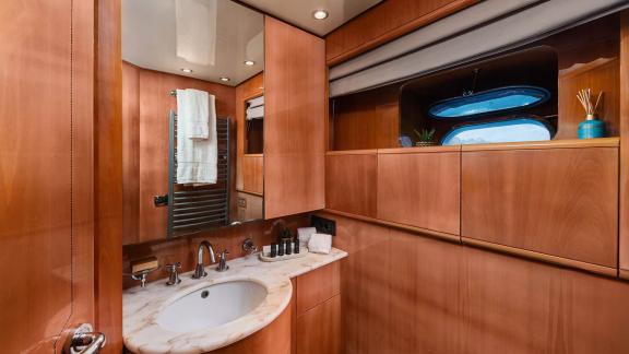 The bathroom of Dream motor yacht in Athens features a sink, mirror, towel radiator and wooden cabinets.