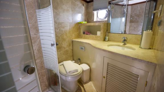Gazella’s bathroom features a marble sink, a glass shower cabin, and a small window.