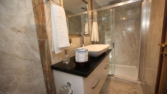 Simay F yatının banyosunda geniş duş kabini, modern lavabo ve şık dekorasyon bulunuyor.