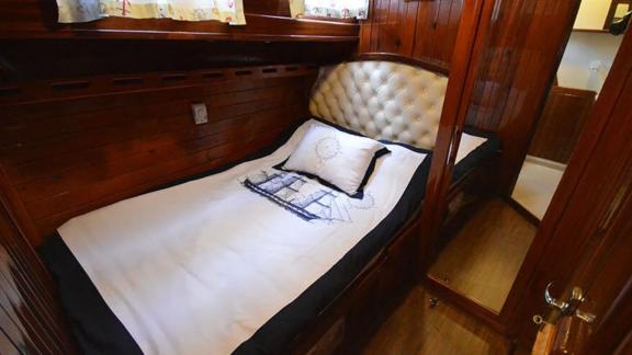 Single cabin with padded headboard and decorative pillows on Gulet Ali Aga 1 in Göcek.