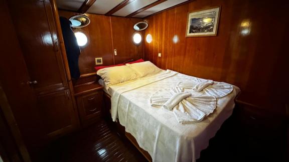 The double cabin of gulet Sea Angel 2 is furnished with wooden cabinets and round portholes.