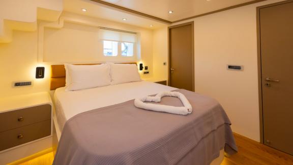 The comfortable bedroom of the luxury trawler Lycian Dream in Fethiye features a large bed and modern design.