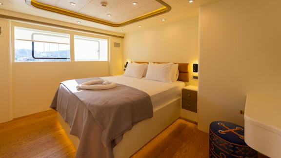 The bright bedroom of the luxury trawler Lycian Dream in Fethiye features large windows and a comfortable bed.