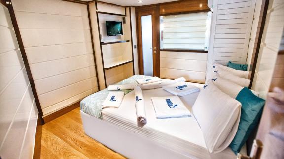 The modern guest cabin of Maske 2 features a comfortable bed and a flat-screen TV.