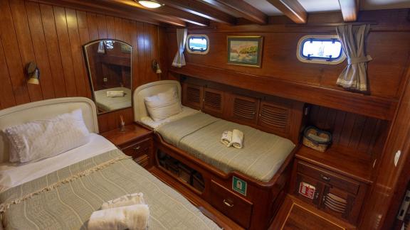 Cozy twin bed cabin on the Serenad yacht with elegant wood decor and practical layout.