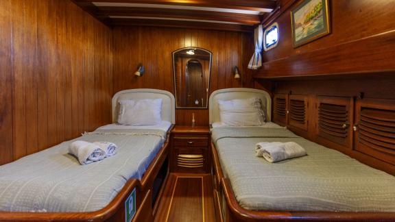 Elegant twin bed cabin on the Serenad yacht with wood decor and comfortable amenities.