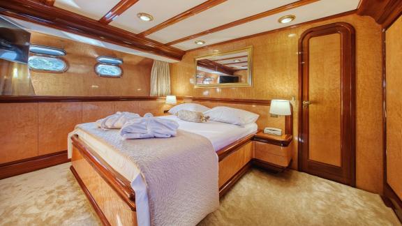 The luxurious bedroom of motor yacht Custom Blanka features a large bed and elegant decor.