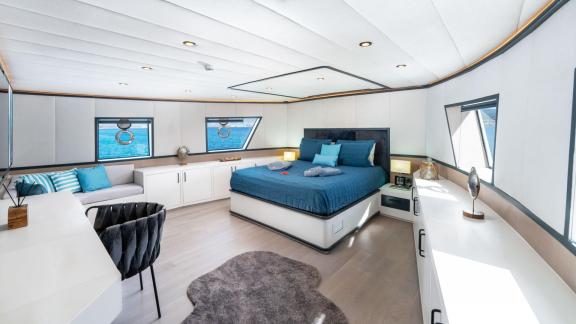 Modernly decorated, spacious yacht bedroom with sea view; includes a comfortable bed, desk, and seating area.
