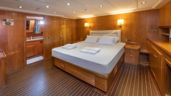 Cosy cabin of a Bodrum Gulet with 5 cabins, equipped with a large bed, wood panelling and warm light.