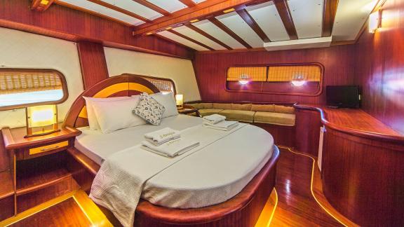 Luxurious cabin on a sailing yacht with a large bed, wooden furniture and stylish lighting.