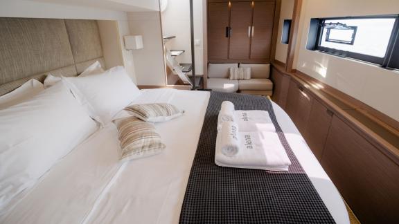 Bright cabin with double bed and cozy seating area on a catamaran.