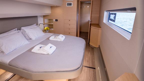 Elegant cabin with a large bed and sea view window on a luxurious catamaran, equipped with amenities.