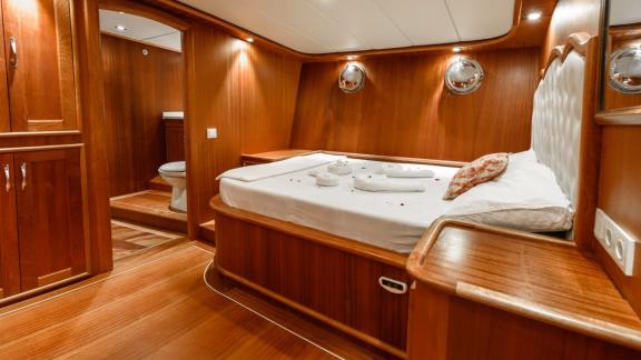 A stylish and comfortable cabin on the Gulet Anıl Kaptan 1 with wood paneling and a private bathroom.