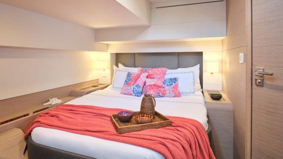 Tastefully decorated cabin on the catamaran with a double bed, decorative pillows, and a soft blanket.