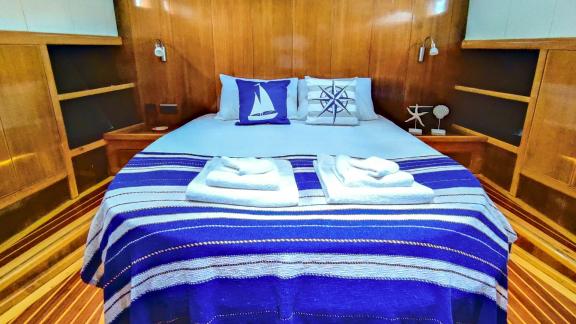 Cozy cabin with double bed, blue bedspread, and nautical pillows on Gulet Cagan 2.