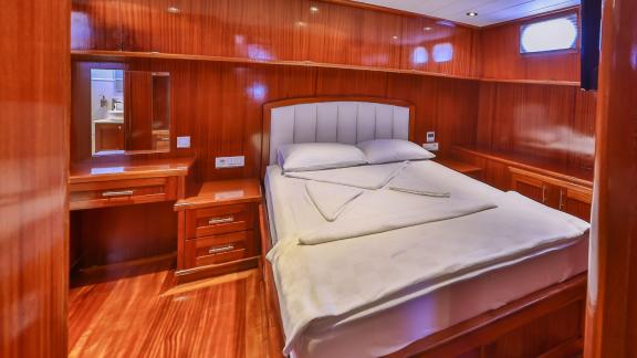 A cozy cabin with a double bed and wooden paneling on the Gulet Kasapoglu 6.