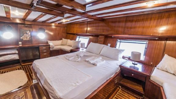 Luxurious master cabin with a large bed and cozy seating areas on the Gulet Optimist in Bodrum.