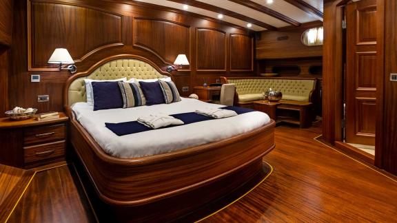 Spacious cabin with elegant wooden interior, comfortable double bed, seating area and stylish lighting.