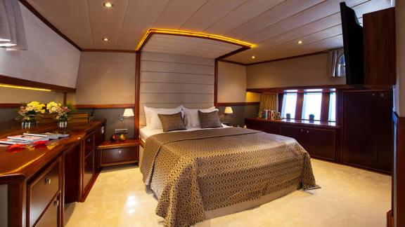 Elegant bedroom on the sailing yacht with a large bed and stylish decor.