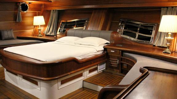 Cabin of the Grande Mare with large bed, stylish wood panelling and cosy lighting.