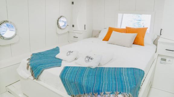 Bright and elegant bedroom of Gulet Mehmet Bey 1 with a cozy atmosphere and porthole windows.