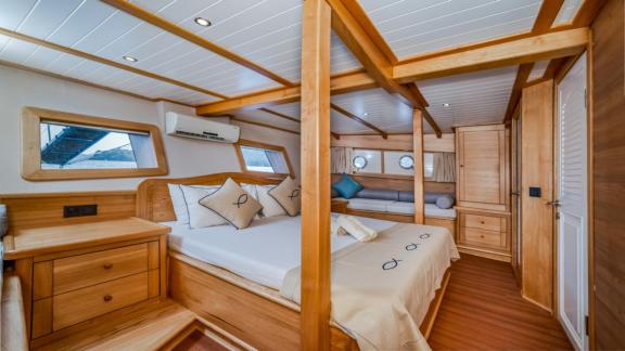 A bright, spacious bedroom on the gulet yacht Amazon Solo with double bed and wooden furniture.