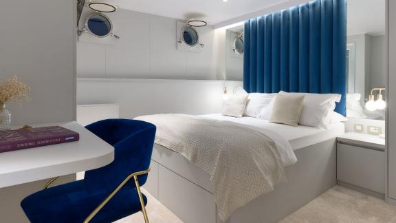 Stylish cabin on the Bellezza yacht with a comfortable bed, blue chair, and elegant decor.