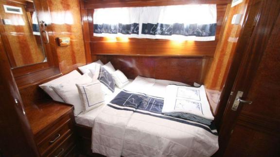 Comfortable double cabin on Gulet Miramare with elegant wood paneling and nautical-themed bedding.