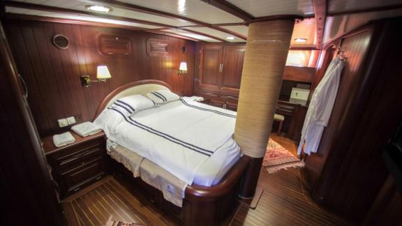 A luxurious cabin on board the Gulet Dulcinea with a large, cosy bed and elegant wood panelling.