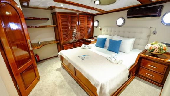 Cosy saloon on a yacht with a dining table, green chairs and a comfortable sofa.