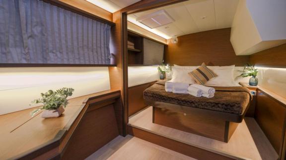 Tastefully furnished cabin with a double bed, plants, and soft lighting on the Daphne catamaran.