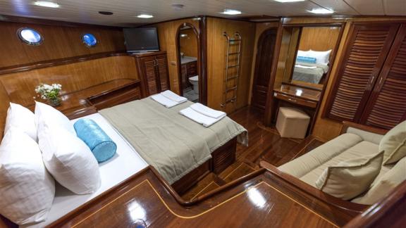 Luxuriöse Kabine auf der Yacht Kayhan mit Doppelbett, Sofa und eigenem Bad, ideal für komfortable Nächte.