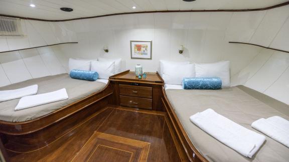 Spacious double cabin on the gulet with two large beds and elegant wooden decor.