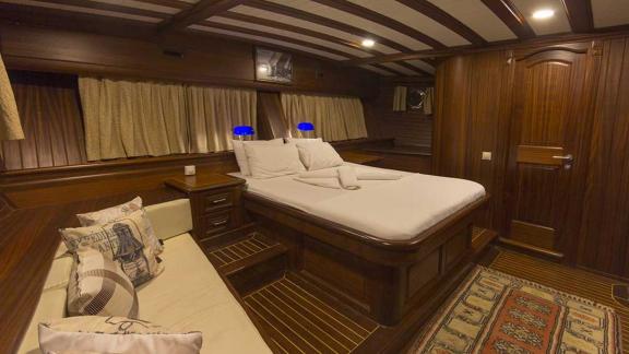 Comfortable cabin with a large bed, wood panelling.