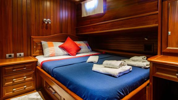 Comfortable cabin of the 24-meter Gulet Sani Kaptan 2 with double bed and wood paneling, perfect for restful nights in B