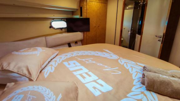 Ein weiterer Blickwinkel der Hauptkabine der Motoryacht Zeus 2 mit einem bequemen Bett und Fernseher.