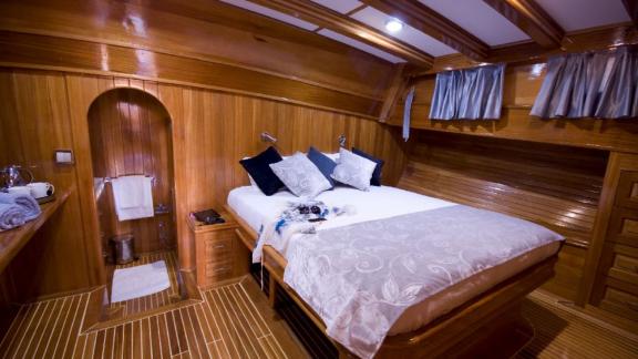 An elegant and well-equipped cabin on board the Flas VII, with a cosy double bed and high-quality wood panelling.