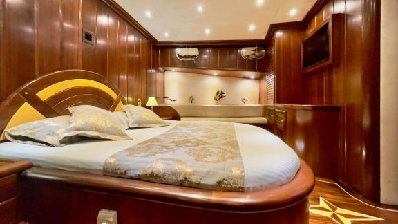 Luxurious master cabin of the Gulet Diva Deniz with elegant double bed and fine wood panelling.