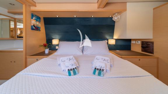 Comfortable double bed with white linens and decorative folded towels in a warm wood-tone cabin.