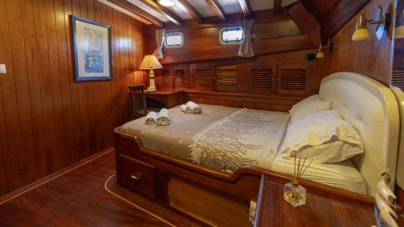 Hochwertig eingerichtete Kabine auf der Yacht Serenad mit gemütlichem Doppelbett und eleganter Holzausstattung.