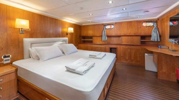 A spacious cabin on a Bodrum gulet with a large bed and wood panelling.